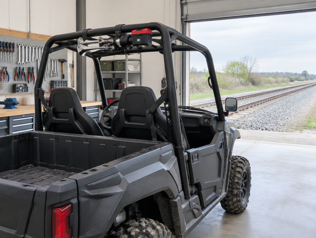 UTV with a train horn clamped to its roll cage, parked in a bright rail workshop with the door open to the track.