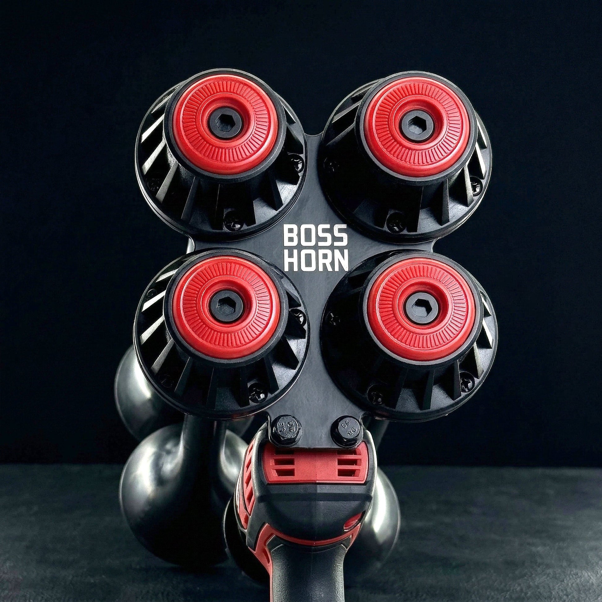 Front view of the four red-and-black trumpet horns with curved bells below, mounted on the unit against a dark gray background