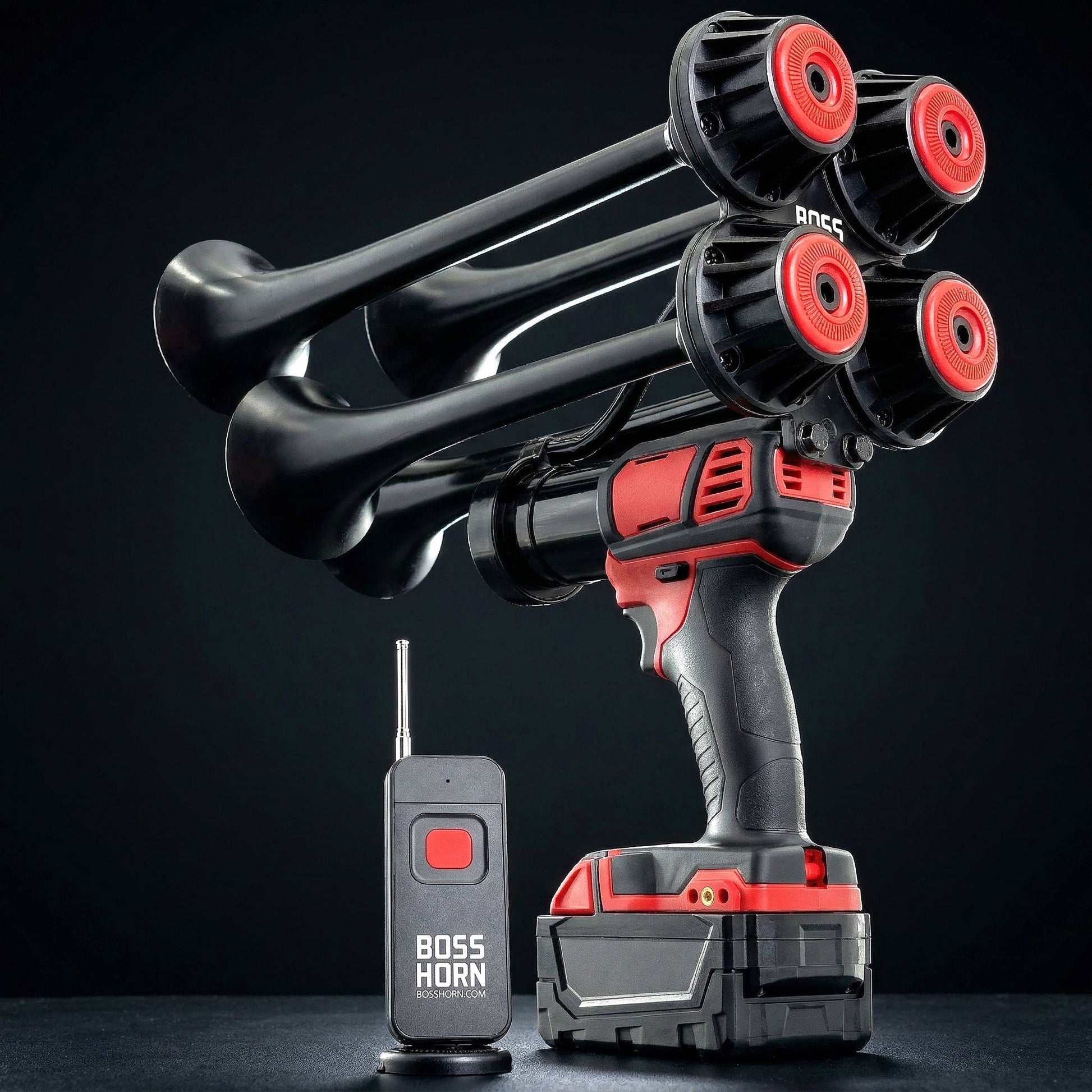 Boss Series quad-trumpet train horn with red and black trumpets mounted on a cordless power tool, beside a wireless remote on a dark background