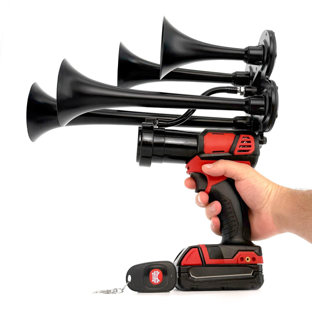 Hand holding the black four-trumpet train horn by its cordless tool grip with key-fob remote and Milwaukee® M18 battery