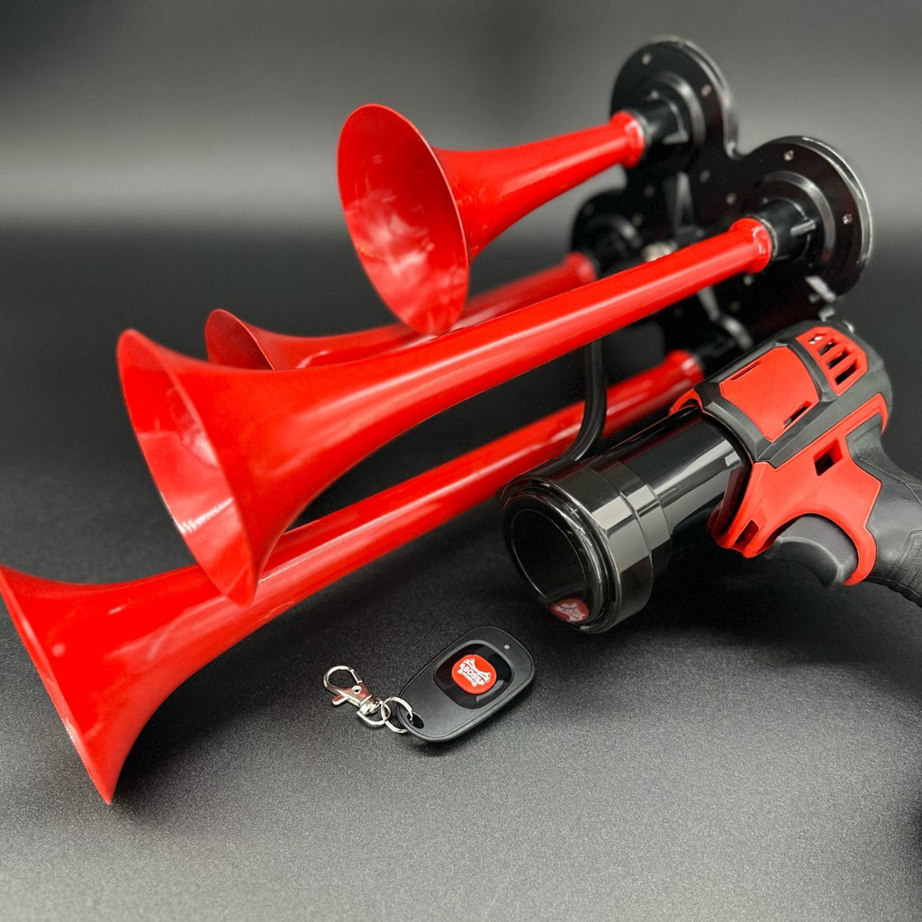 Angled view of the four red trumpets and black horn unit on a cordless tool with key-fob remote on a gray surface