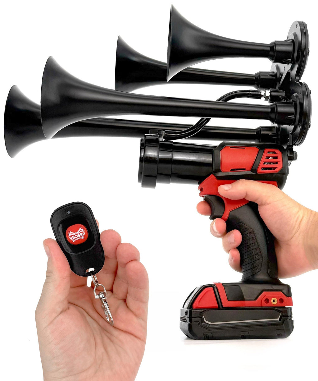 Hand gripping the black quad-trumpet train horn on a cordless tool, holding the small key-fob remote in the other hand